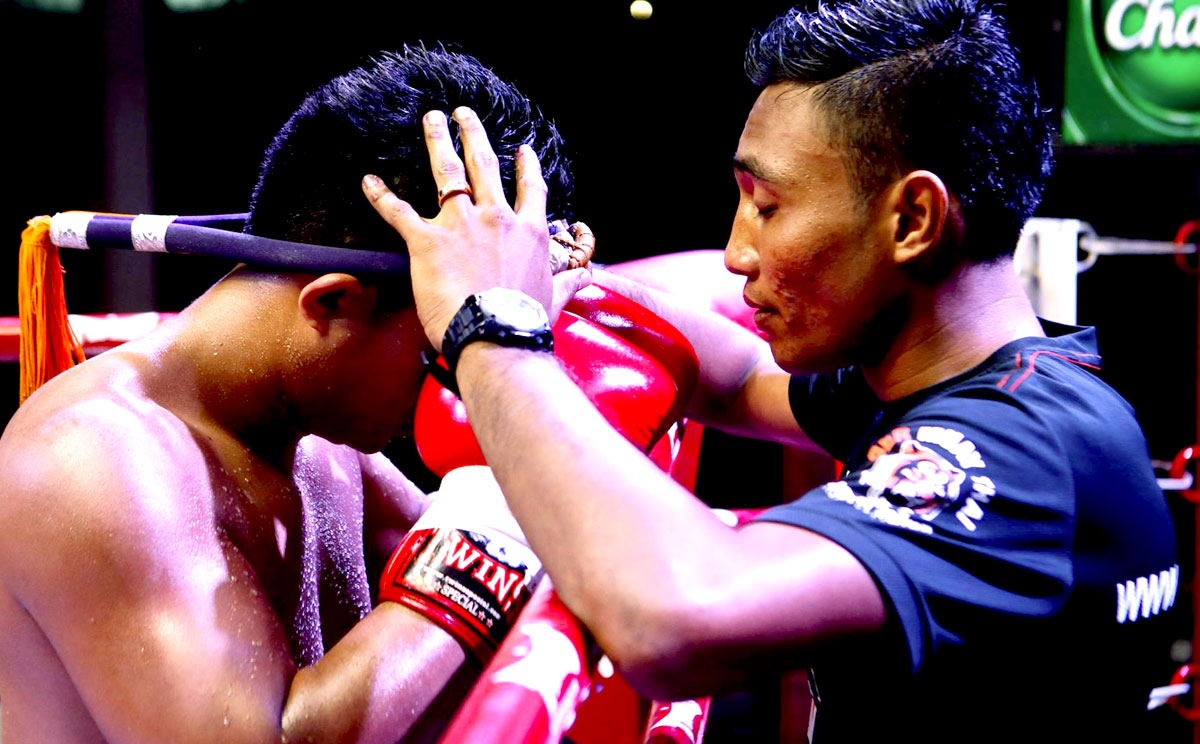 Kru Don performing the pre-fight prayer with the fighter wearing the Mongkong